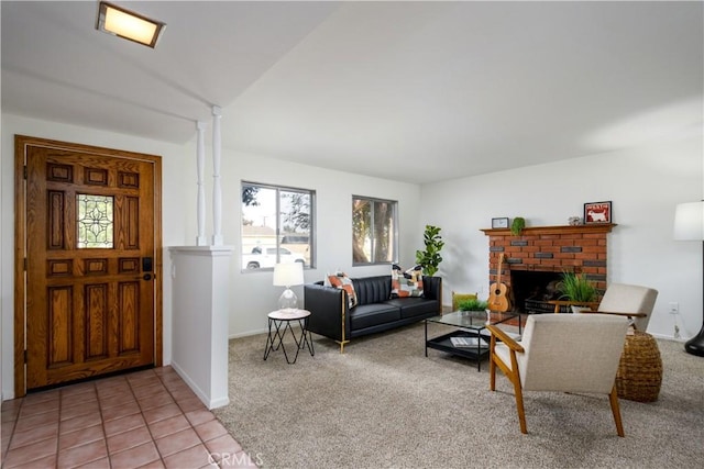 living room featuring ornate columns, vaulted ceiling, a brick fireplace, and light colored carpet