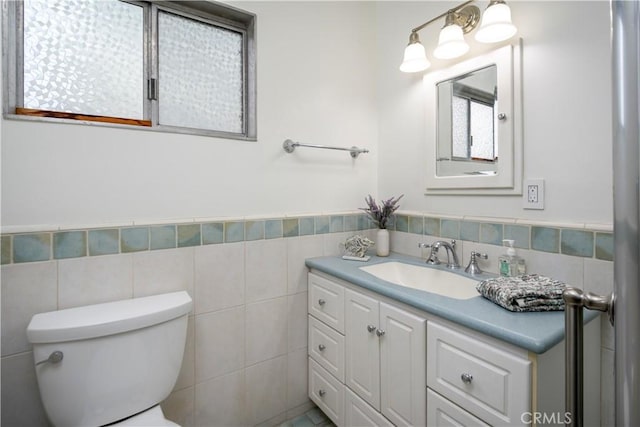 bathroom featuring vanity, toilet, and tile walls