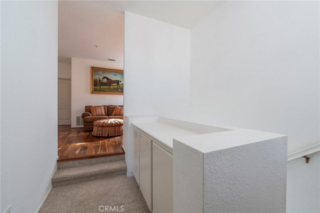 hallway featuring visible vents and light colored carpet