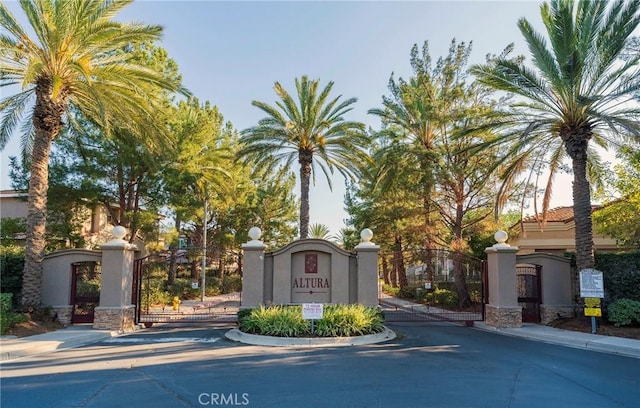 view of street with a gate, a gated entry, and curbs