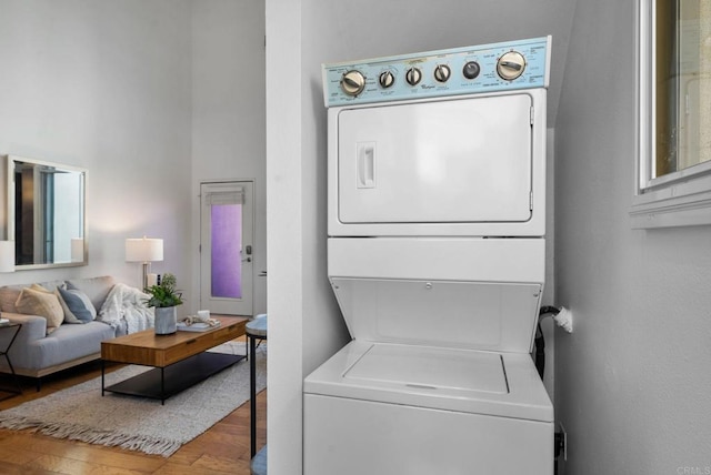 laundry room featuring hardwood / wood-style flooring and stacked washing maching and dryer