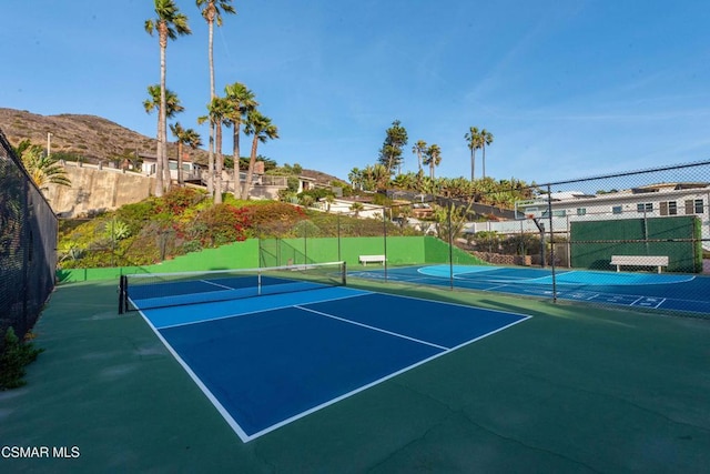 view of tennis court with a mountain view and basketball hoop