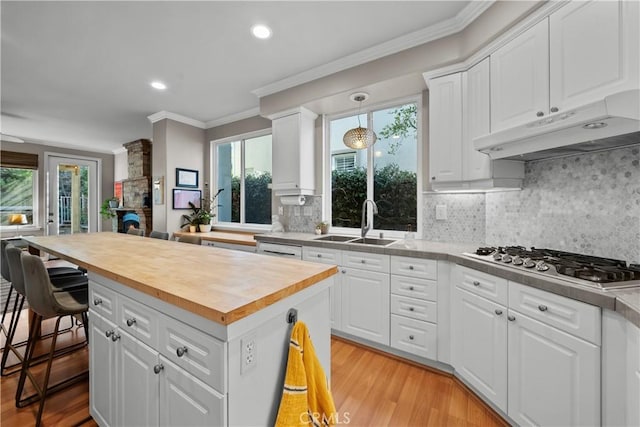 kitchen with white cabinetry, stainless steel gas stovetop, a center island, and wooden counters