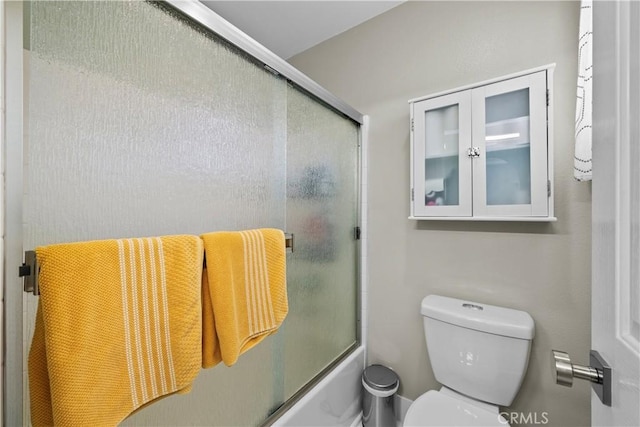 bathroom featuring bath / shower combo with glass door and toilet