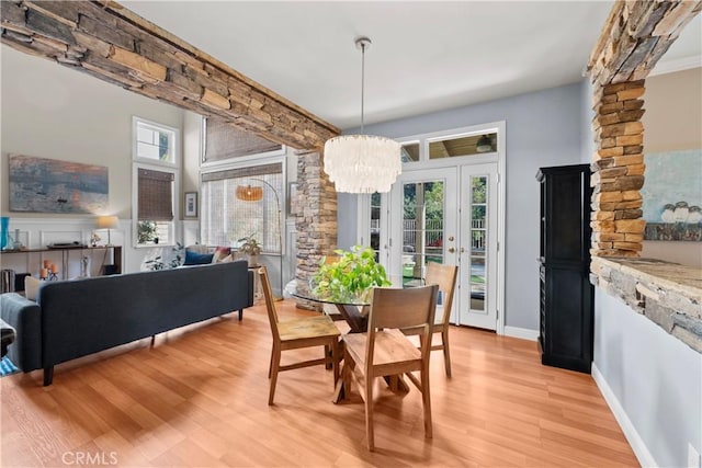 dining area with an inviting chandelier, a wealth of natural light, and light hardwood / wood-style flooring