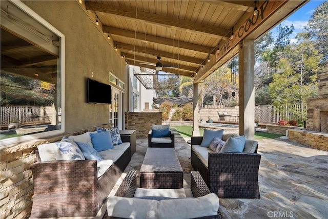 view of patio / terrace with ceiling fan and an outdoor living space with a fireplace