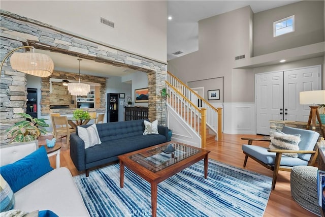 living room featuring a notable chandelier, hardwood / wood-style flooring, and a towering ceiling