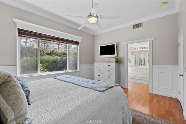 bedroom with crown molding, ceiling fan, light wood-type flooring, and ensuite bath