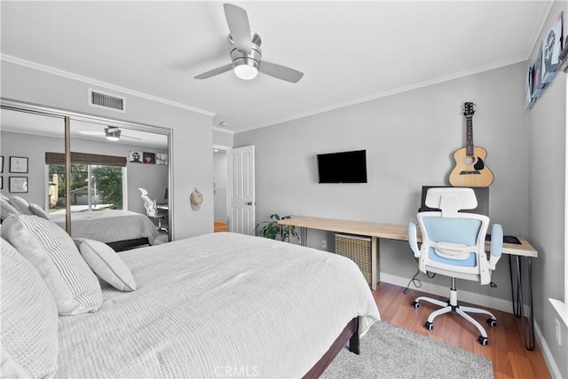 bedroom with hardwood / wood-style flooring, ceiling fan, crown molding, and a closet