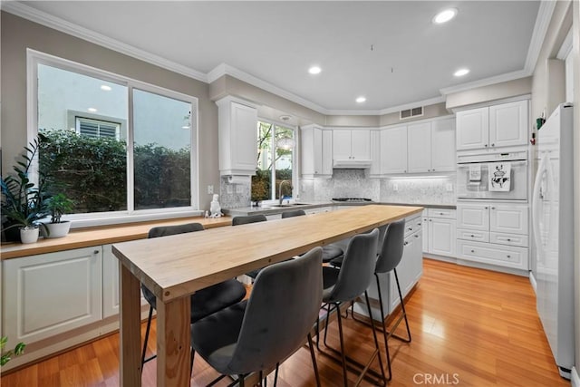 kitchen with butcher block countertops, white cabinetry, tasteful backsplash, light hardwood / wood-style flooring, and white appliances