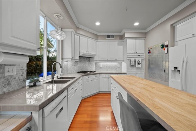 kitchen with sink, crown molding, decorative light fixtures, white appliances, and white cabinets