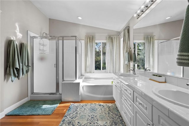 bathroom with lofted ceiling, vanity, wood-type flooring, and plus walk in shower