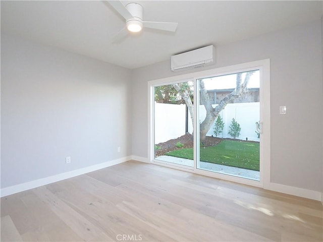 unfurnished room with ceiling fan, light wood-type flooring, and a wall unit AC