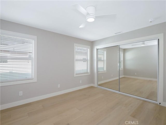 unfurnished bedroom featuring ceiling fan, light wood-type flooring, and a closet