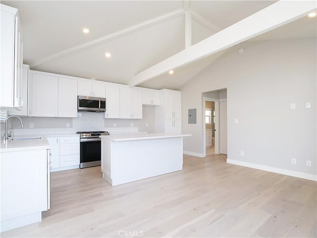 kitchen featuring sink, beam ceiling, stainless steel appliances, white cabinets, and a kitchen island