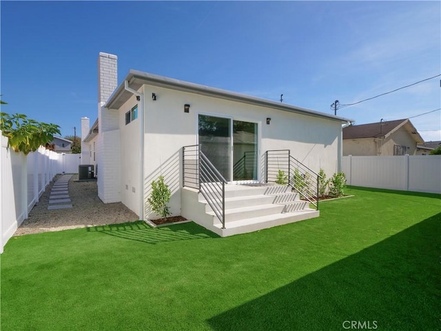 rear view of property featuring central AC unit and a lawn