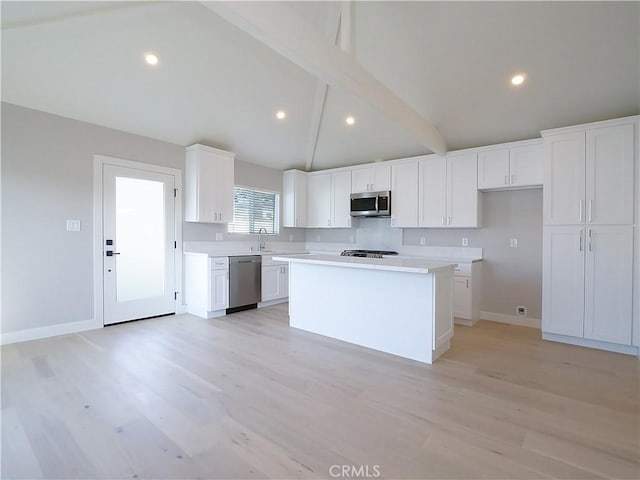 kitchen featuring white cabinetry, light hardwood / wood-style flooring, appliances with stainless steel finishes, a kitchen island, and beamed ceiling