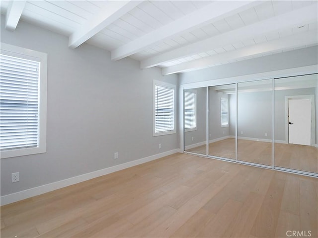 unfurnished bedroom with wood ceiling, light hardwood / wood-style floors, a closet, and beamed ceiling