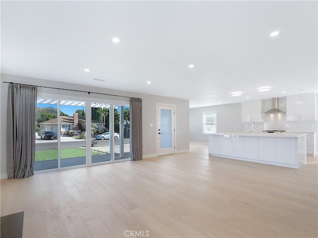 unfurnished living room with plenty of natural light, sink, and light hardwood / wood-style floors