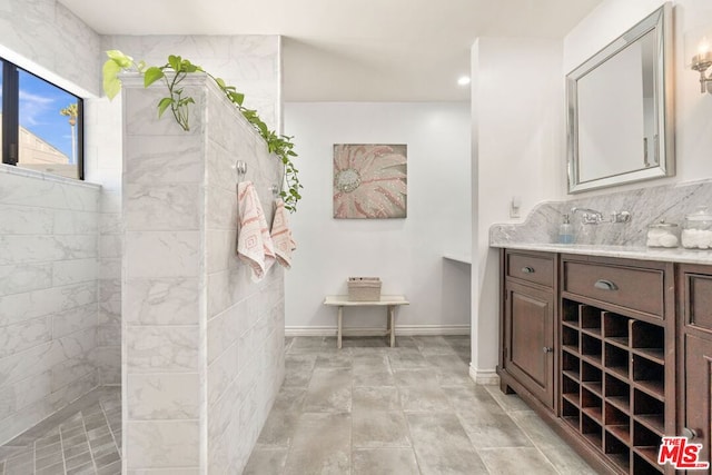 bathroom with vanity, decorative backsplash, and a tile shower