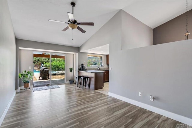 interior space featuring ceiling fan, high vaulted ceiling, and light hardwood / wood-style floors