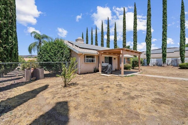 back of property featuring solar panels, a fenced backyard, a pergola, and a patio area