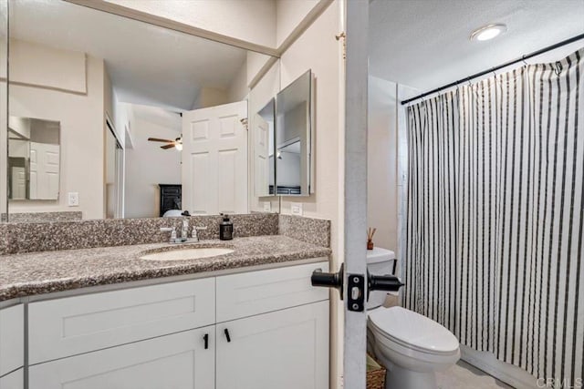 bathroom with walk in shower, ceiling fan, vanity, and toilet