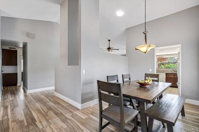 dining area with high vaulted ceiling, ceiling fan, and light wood-type flooring