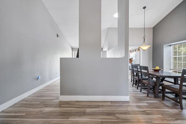 dining room with visible vents, baseboards, a high ceiling, and wood finished floors