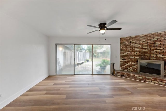 unfurnished living room with a brick fireplace, ceiling fan, and light hardwood / wood-style flooring