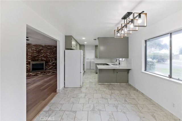 kitchen with sink, gray cabinetry, a kitchen breakfast bar, white fridge, and kitchen peninsula