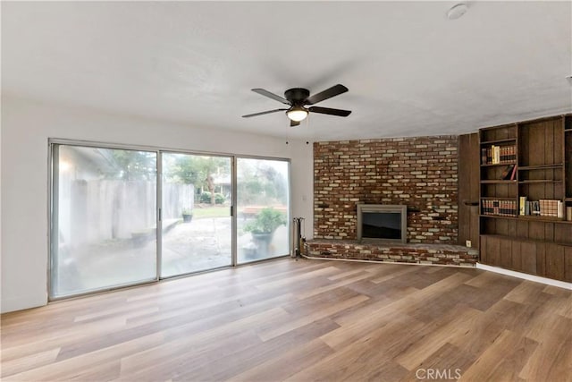 unfurnished living room with a brick fireplace, light hardwood / wood-style floors, and ceiling fan