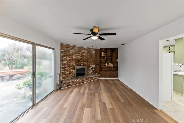 unfurnished living room featuring ceiling fan, hardwood / wood-style floors, and a brick fireplace