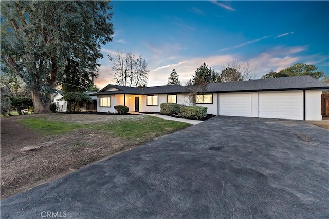 single story home featuring a garage and a lawn