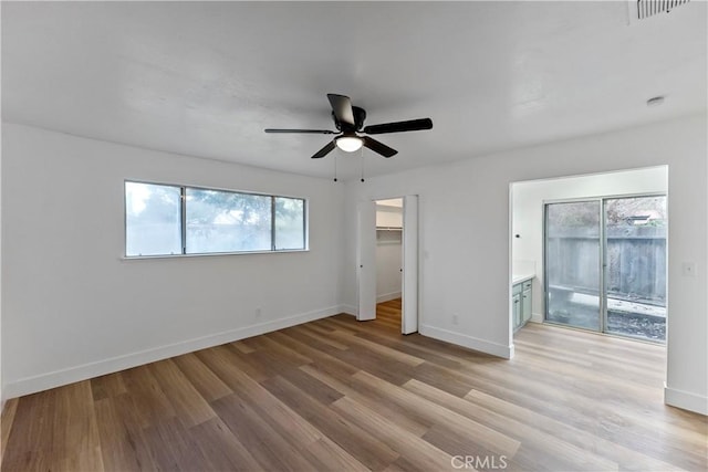 unfurnished bedroom with ceiling fan, a spacious closet, and light wood-type flooring