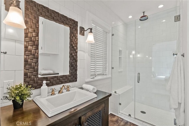 bathroom featuring decorative backsplash, a shower with door, sink, and tile walls