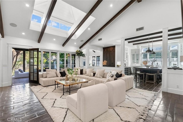 living room with beamed ceiling, a skylight, high vaulted ceiling, and french doors