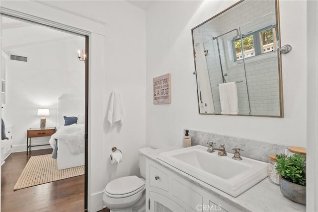 bathroom with hardwood / wood-style flooring, vanity, toilet, and a shower with shower door