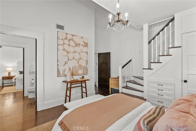 bedroom with a towering ceiling, dark wood-type flooring, and a chandelier