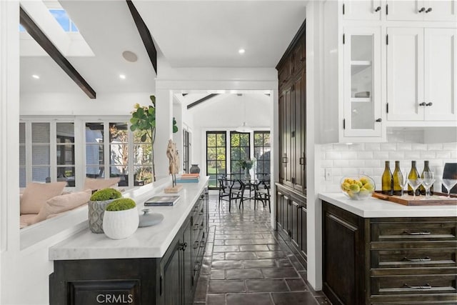 kitchen with tasteful backsplash, lofted ceiling with skylight, and white cabinets