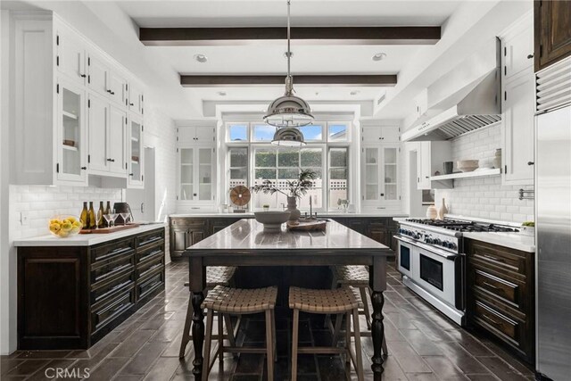 kitchen featuring dark brown cabinetry, a center island, high quality appliances, wall chimney range hood, and white cabinets