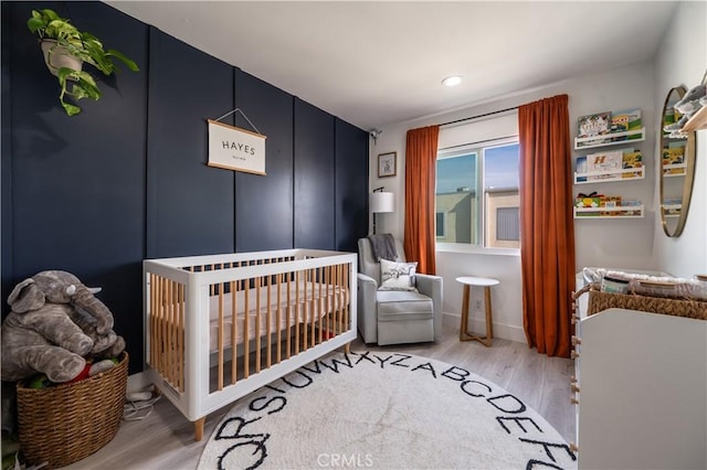 bedroom featuring hardwood / wood-style flooring and a nursery area