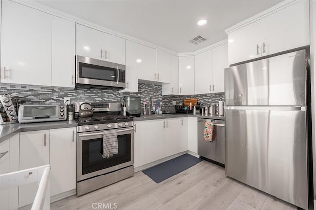 kitchen featuring sink, decorative backsplash, white cabinets, and appliances with stainless steel finishes