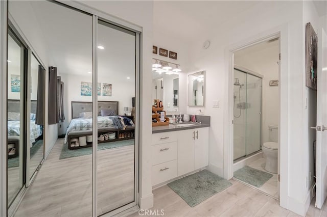 bathroom featuring walk in shower, vanity, toilet, and hardwood / wood-style floors