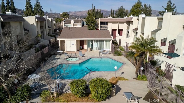 view of swimming pool with a mountain view, a community hot tub, and a patio