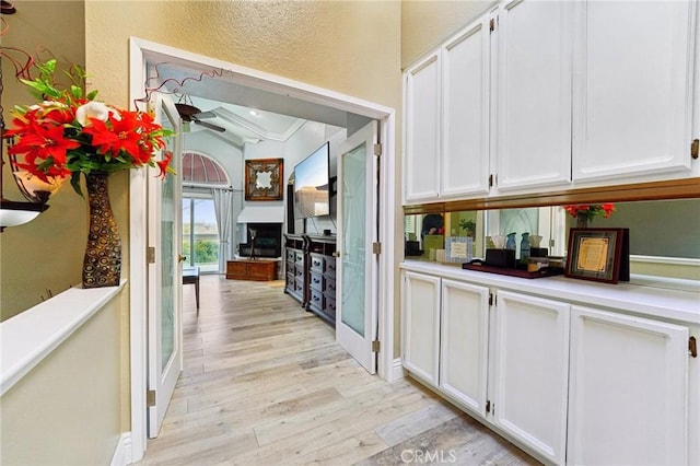 corridor with crown molding, a textured wall, and light wood finished floors