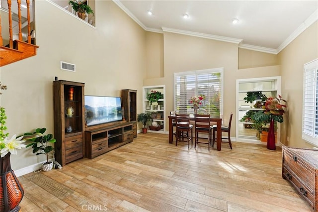 living room featuring baseboards, ornamental molding, visible vents, and light wood-style floors