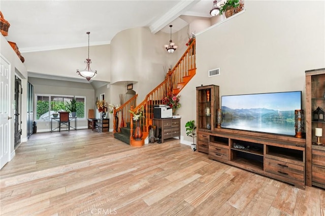 living room with baseboards, visible vents, wood finished floors, stairs, and high vaulted ceiling