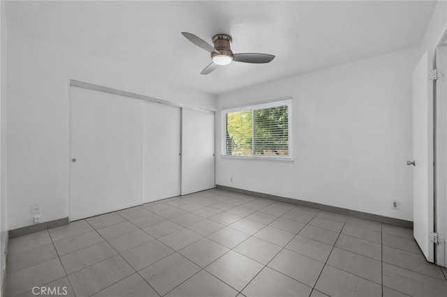 unfurnished bedroom with baseboards, a closet, a ceiling fan, and tile patterned floors