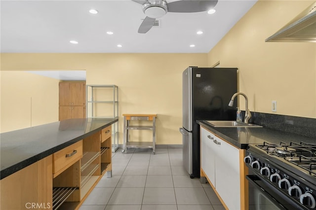 kitchen with a ceiling fan, black gas range oven, dark countertops, a sink, and light tile patterned flooring